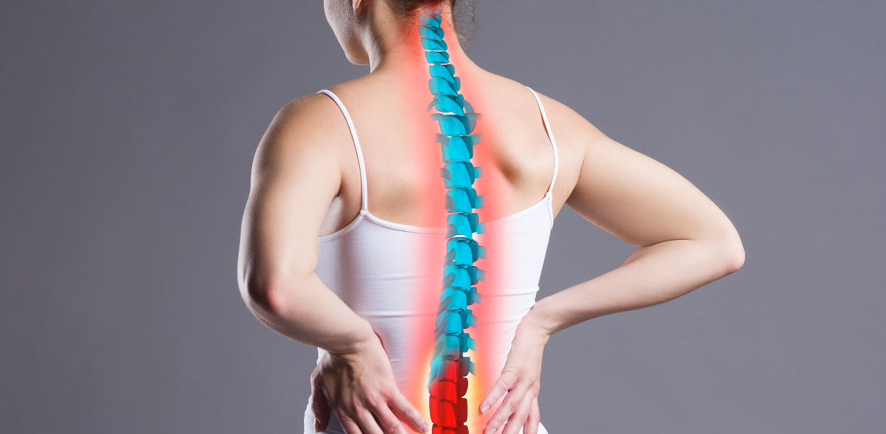 A woman with her back to the camera holding her lower back in pain, with a digital illustration of a spine glowing red, indicating discomfort