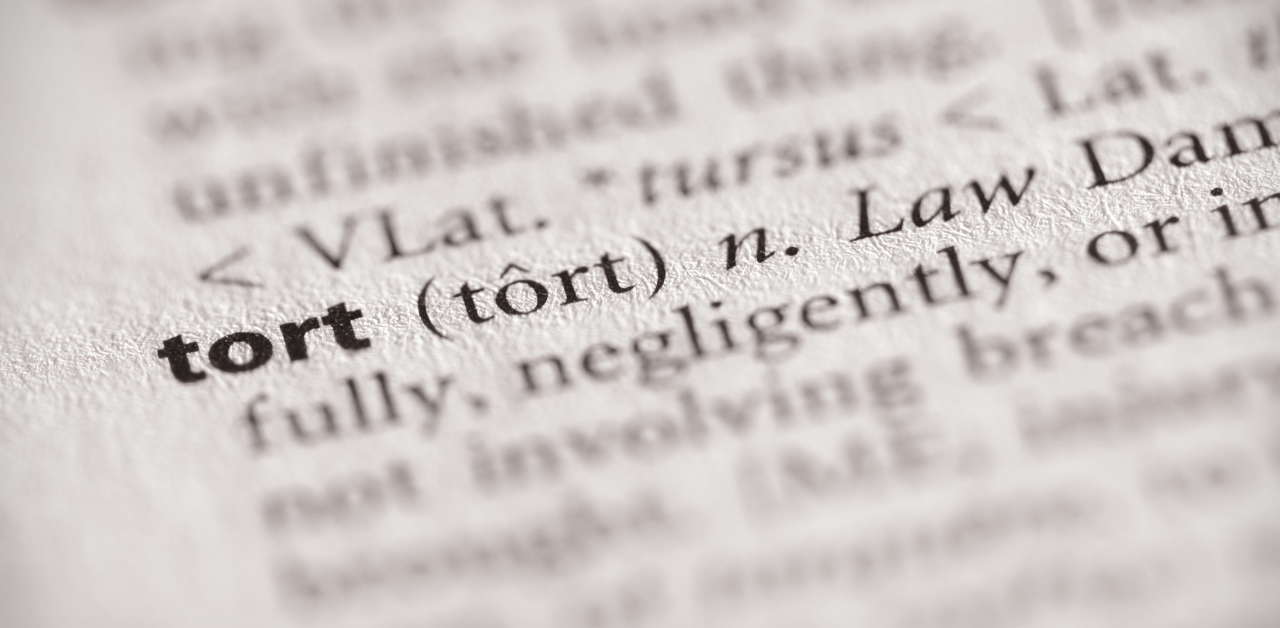 Close-up of the word tort in a dictionary, with its pronunciation and legal definition in focus