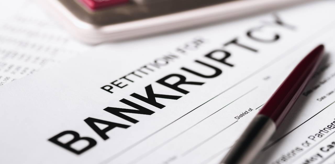 A close-up of a bankruptcy petition form with a pen placed on top, symbolizing financial distress