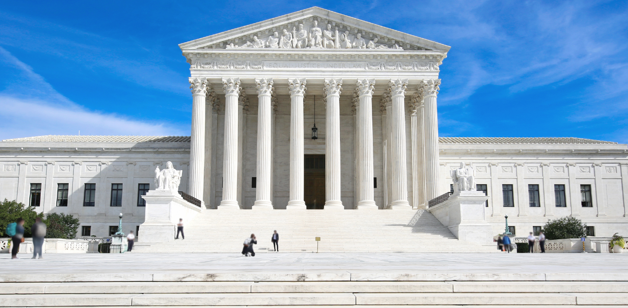 Front view of the U.S. Supreme Court building with white marble columns and people walking outside
