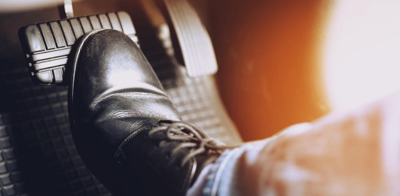 Driver's foot presses down on a car brake pedal, emphasizing road safety and vehicle control