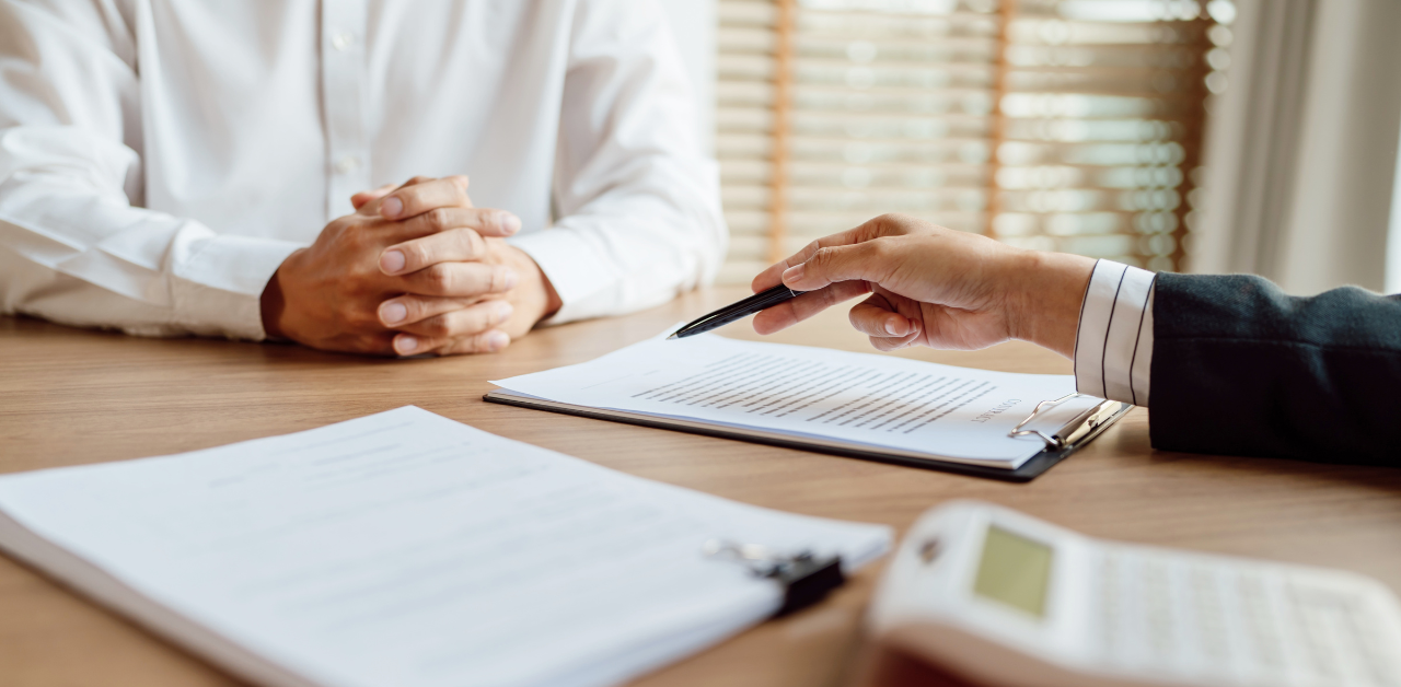 Close-up of a person reviewing and signing legal documents at a desk