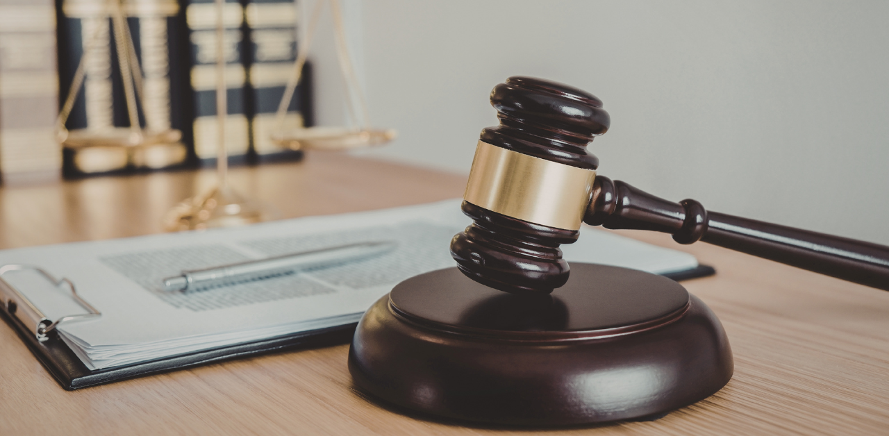 Judge gavel on desk beside legal contract and scales of justice