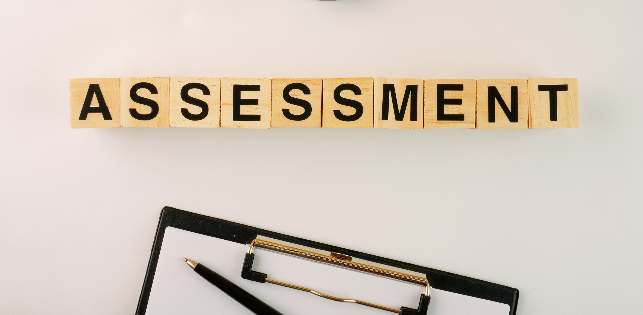 Wooden letter tiles spelling assessment above clipboard and penWooden letter tiles spelling assessment above clipboard and pen