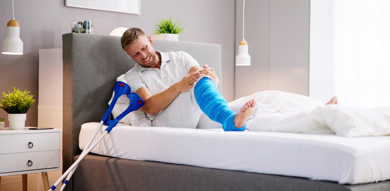 Man with leg cast using crutches while recovering from injury at home
