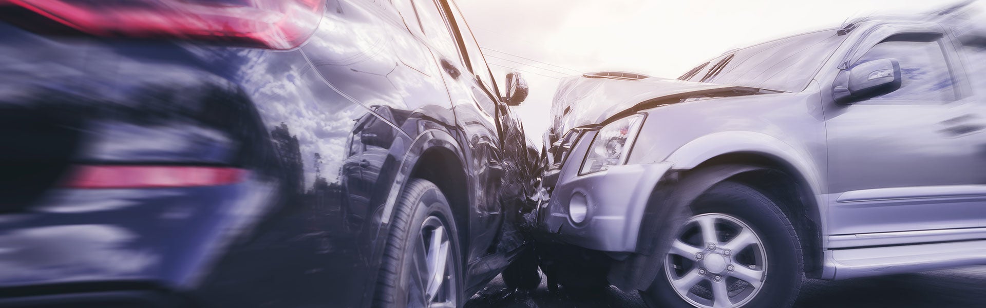Two damaged cars after a collision, the dark car's side is dented into the silver car's front.