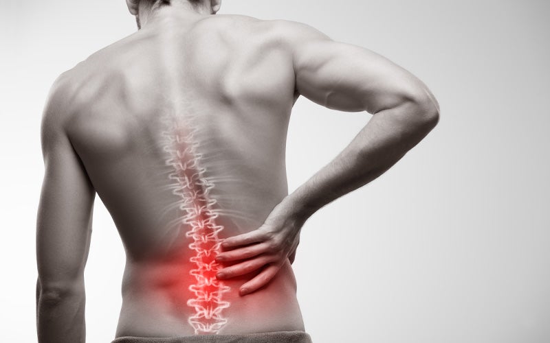 Man clutching his lower back in pain, with his spine highlighted and the painful area glowing red.