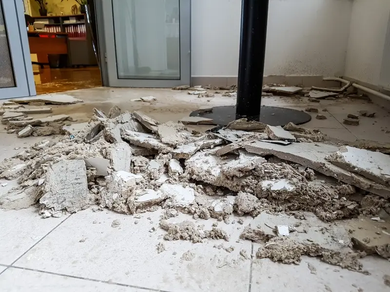 A pile of crumbled and broken drywall pieces on a tiled floor, suggesting recent demolition or damage.