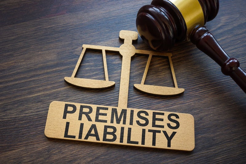 A gavel resting on a wooden desk beside a document titled Premises Liability, illustrating the legal concept.